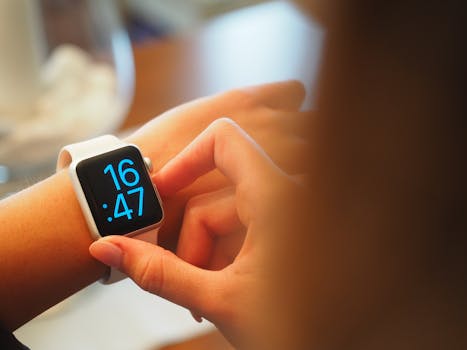 An individual operating a digital smartwatch displaying time with a blue interface.