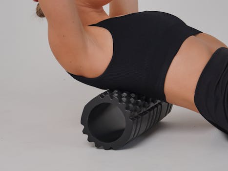 Adult woman practicing workout therapy with a foam roller on a white background.