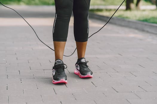 Close-up of feet in sneakers jumping rope on outdoor pavement.