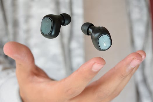 Close-up of levitating black wireless earbuds above an open palm.