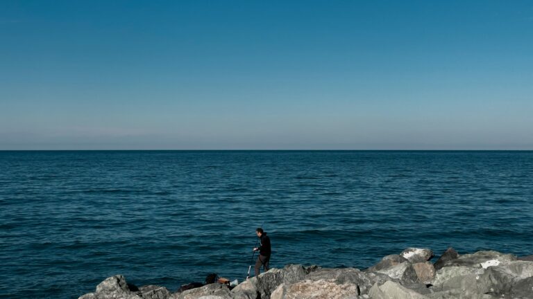 Peaceful seascape in Arhavi, Türkiye with a lone fisherman on the rocks.