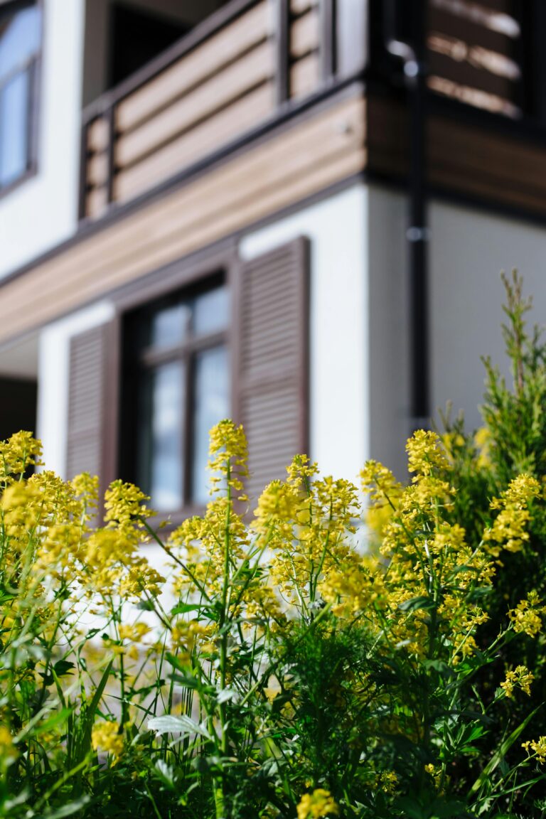 Suburban home with wooden elements and vibrant yellow flowers in focus, perfect for real estate imagery.